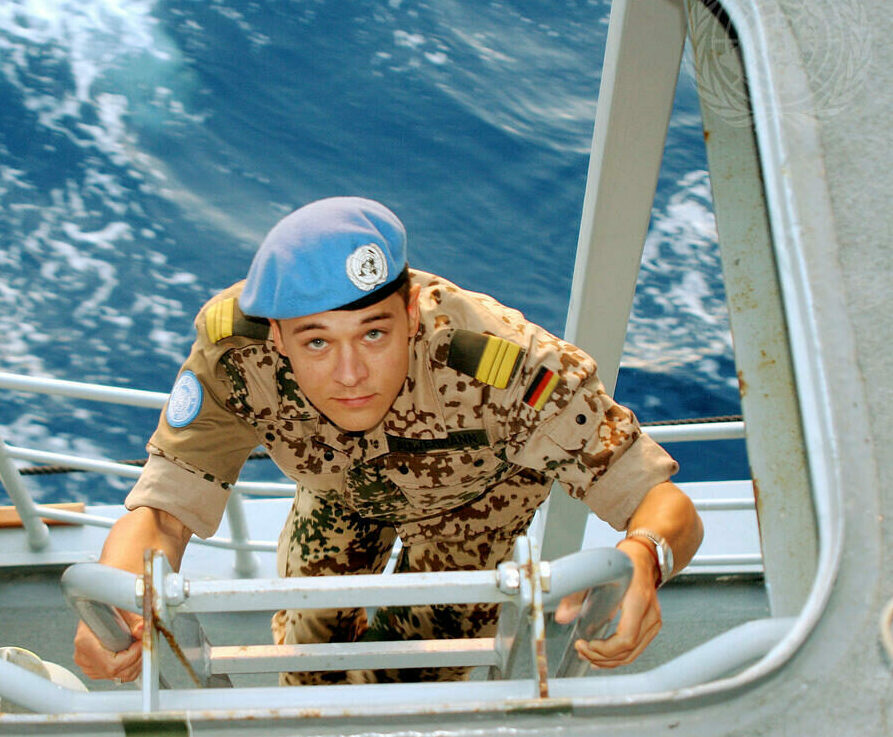 A German Peacekeeper serving with the United Nations climbing up a ladder on a boat.