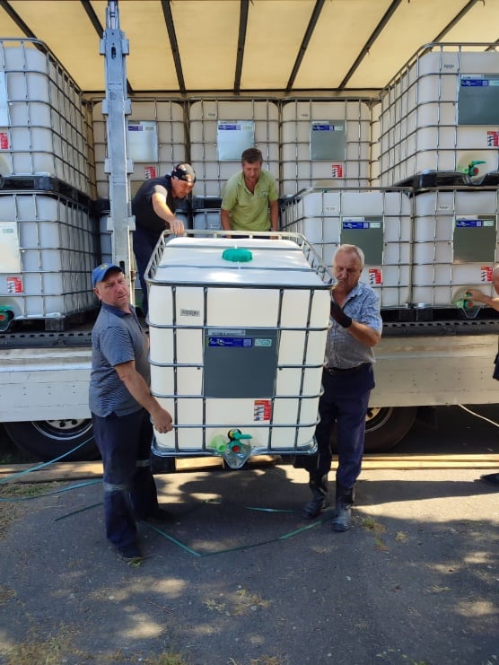 Staff members carrying a water tank out of storage.