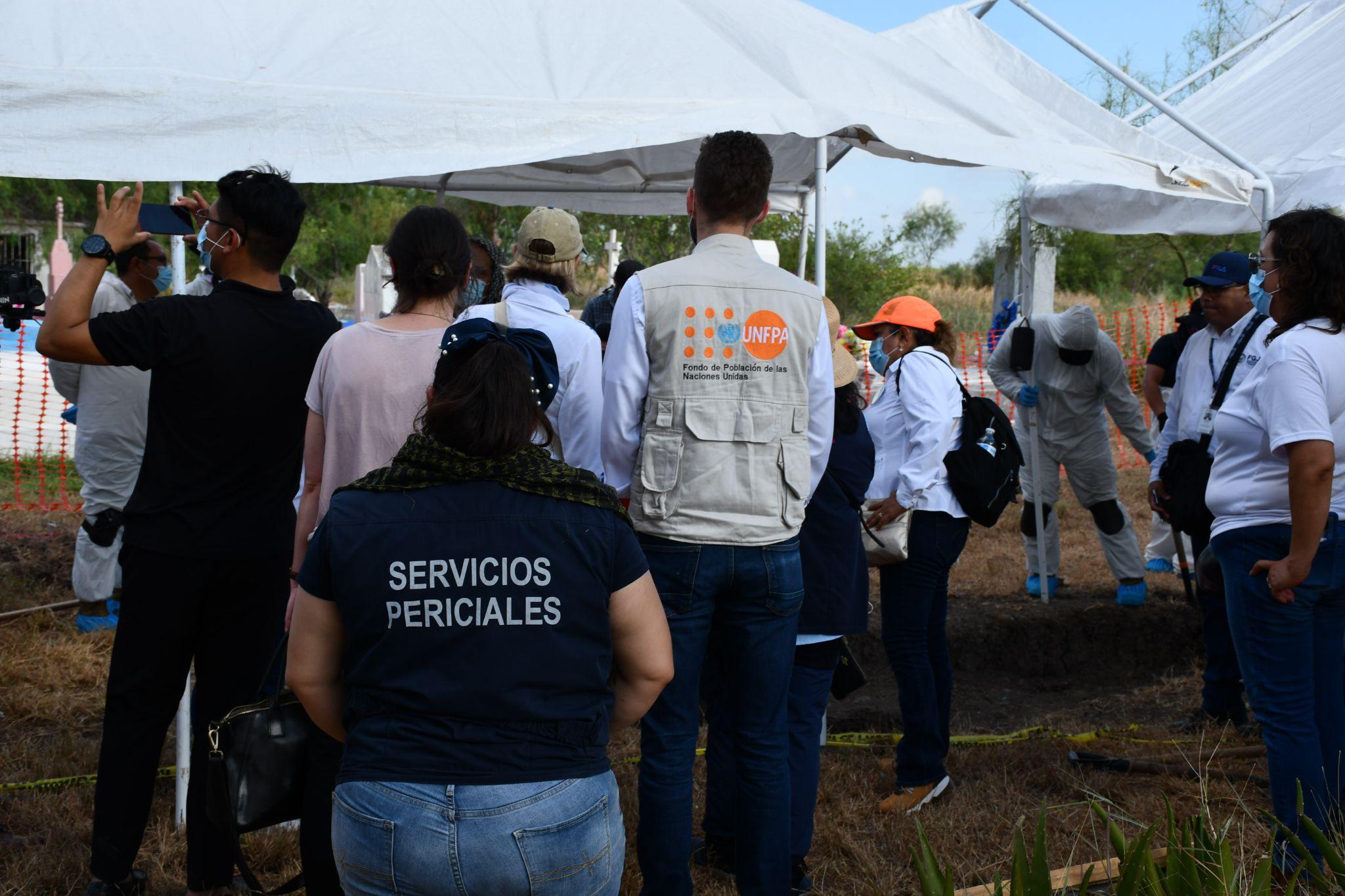 Members of staff are surrounding graves where victims were recovered for post mortem identification.