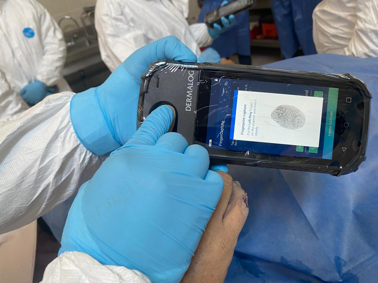 A person holds the finger of a deceased person into the fingerprint scanner.